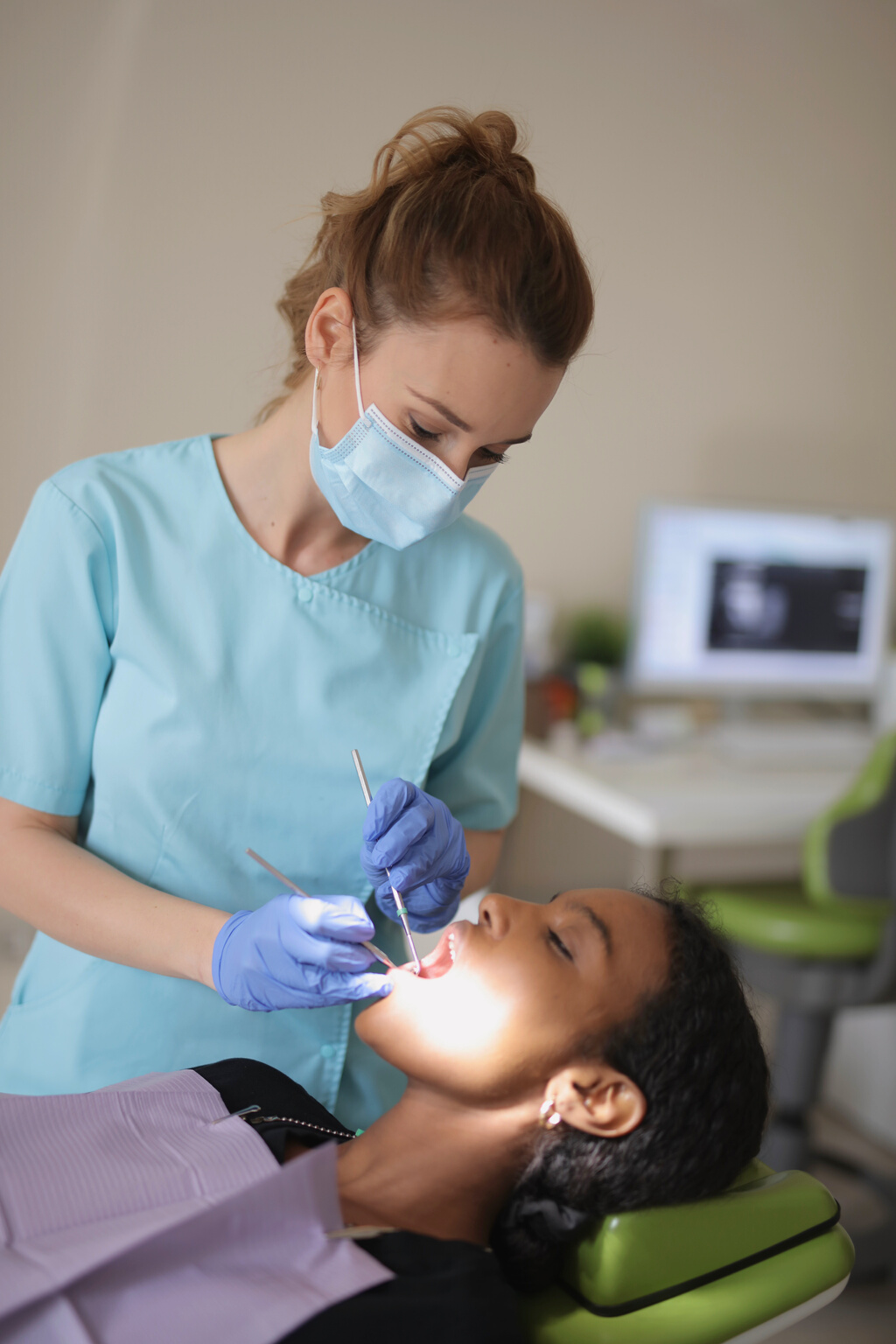 Young female dentist treating teeth of patient in modern clinic